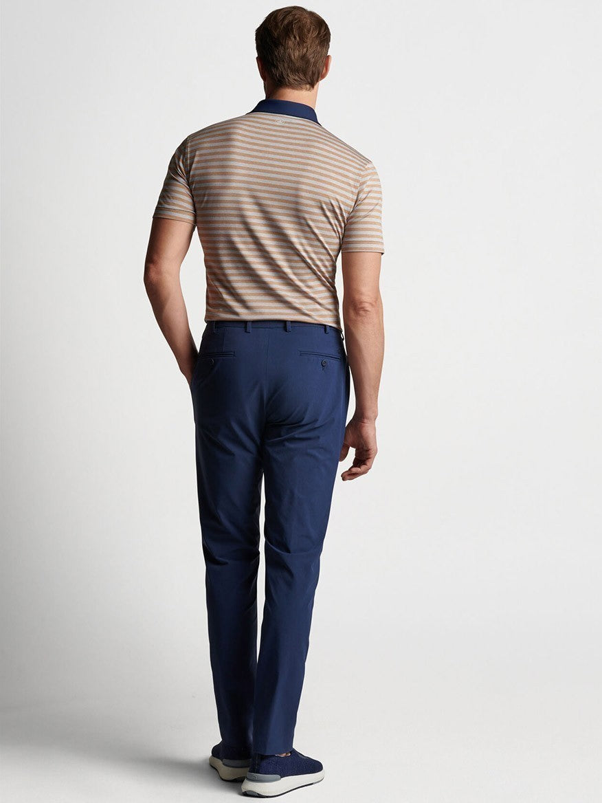 The back view of a man wearing blue Peter Millar Surge Performance Trouser in Navy pants and a striped shirt.