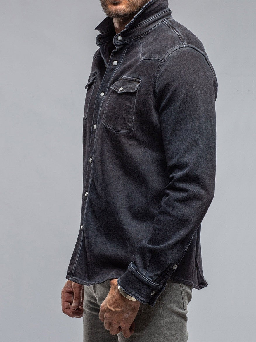 Person wearing a Teleria Zed Roper Western Snap Shirt in Nero and grey pants, standing against a grey background, reminiscent of style mastered by Italian artisans.