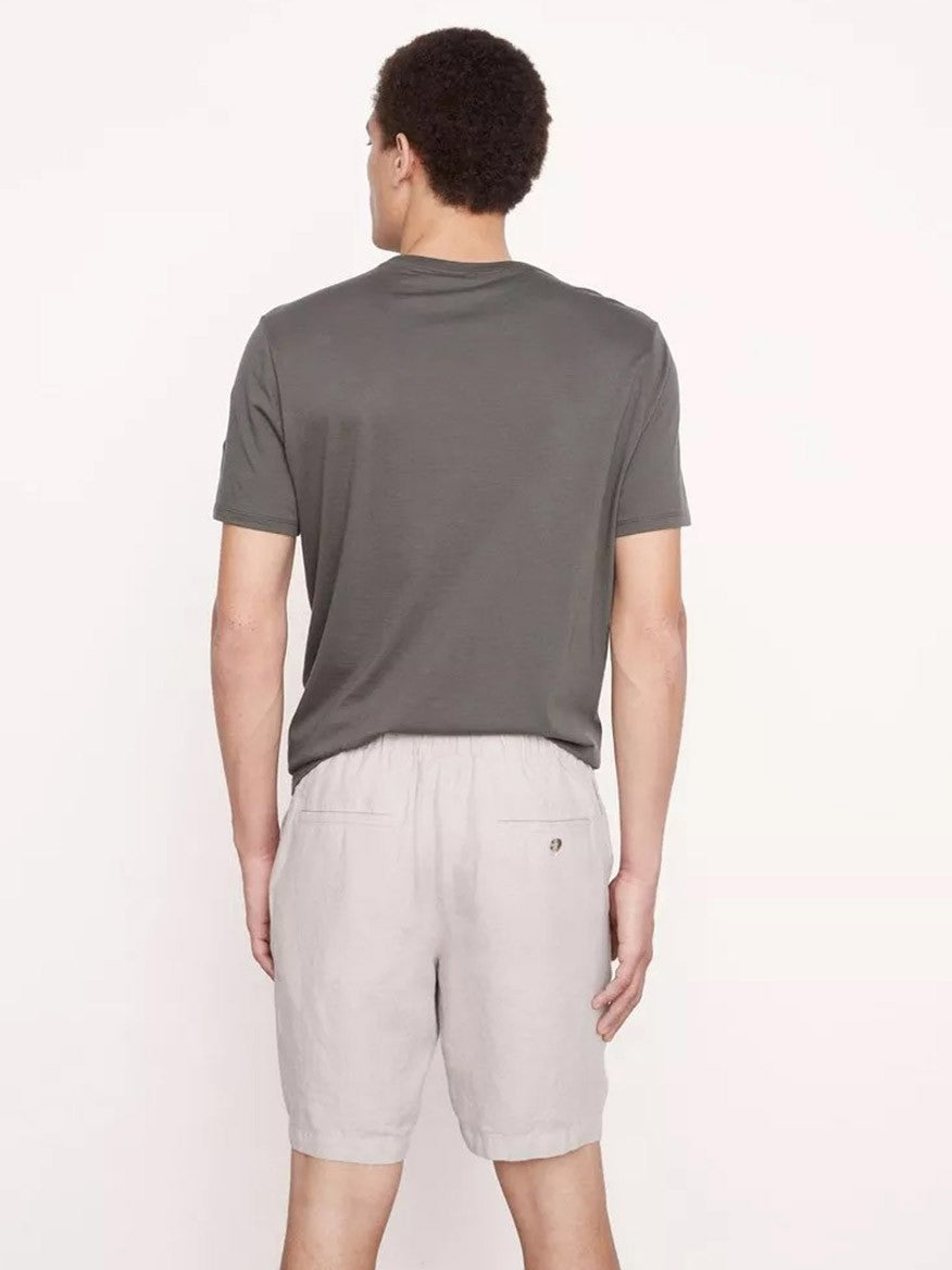 A man standing with his back to the camera, wearing a gray t-shirt and light gray Vince Lightweight Hemp Short in Beach Sand.