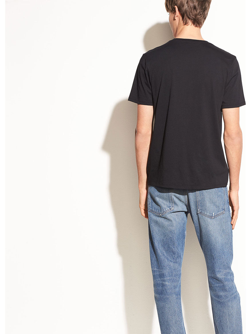 Man wearing a Vince Crew Neck T-Shirt in Black made of pima cotton and blue jeans standing with his back to the camera.