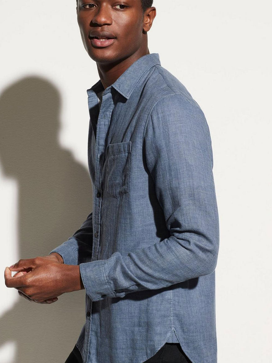 A man in a Vince Double Face Long Sleeve Sport Shirt in Chambray with the sun casting his shadow on a light-colored wall.