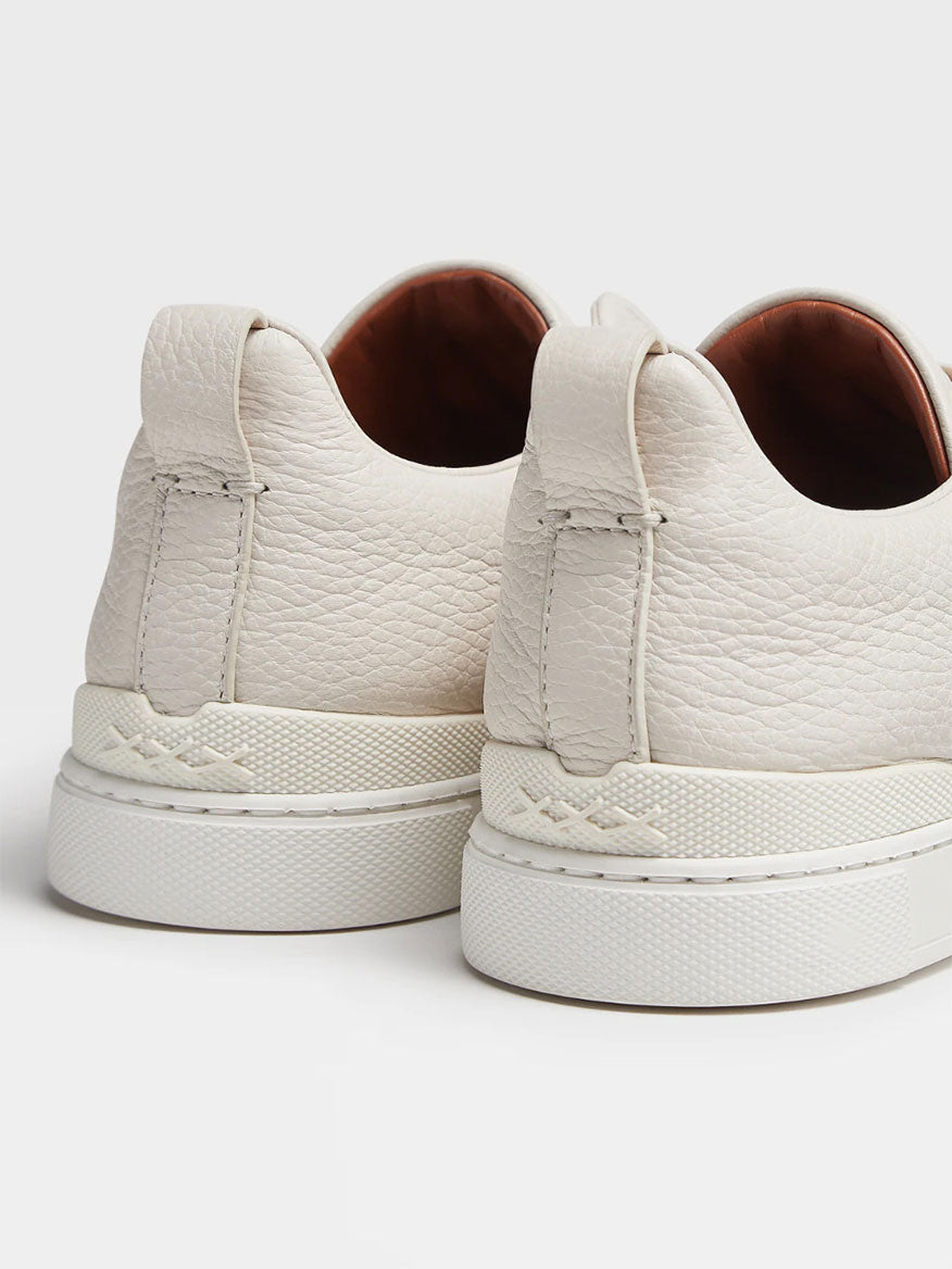 Close-up view of the back of two white textured Zegna Off White Deerskin Triple Stitch™ sneakers with thick soles.