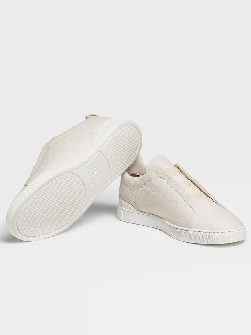 A pair of Zegna Off White Deerskin Triple Stitch™ sneakers displayed against a light gray background.