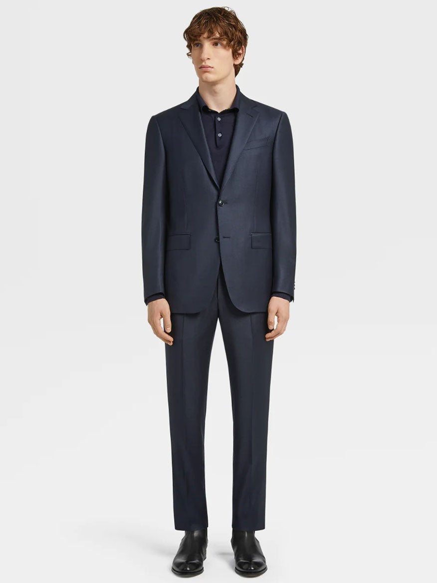 A man in a Zegna Navy Blue Milano Trofeo™ Wool Suit in Pinpoint Pattern and black dress shoes standing against a white background.